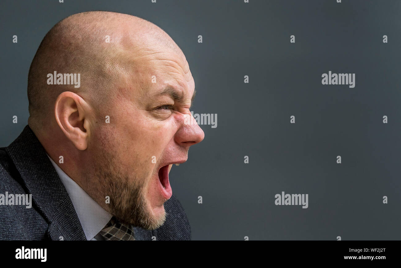 Close-up de empresario frustrado contra un fondo gris Foto de stock