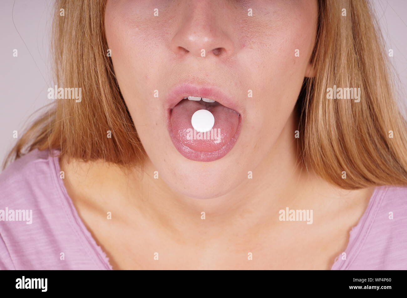 La mitad del torso de mujer con la pastilla en la boca Foto de stock