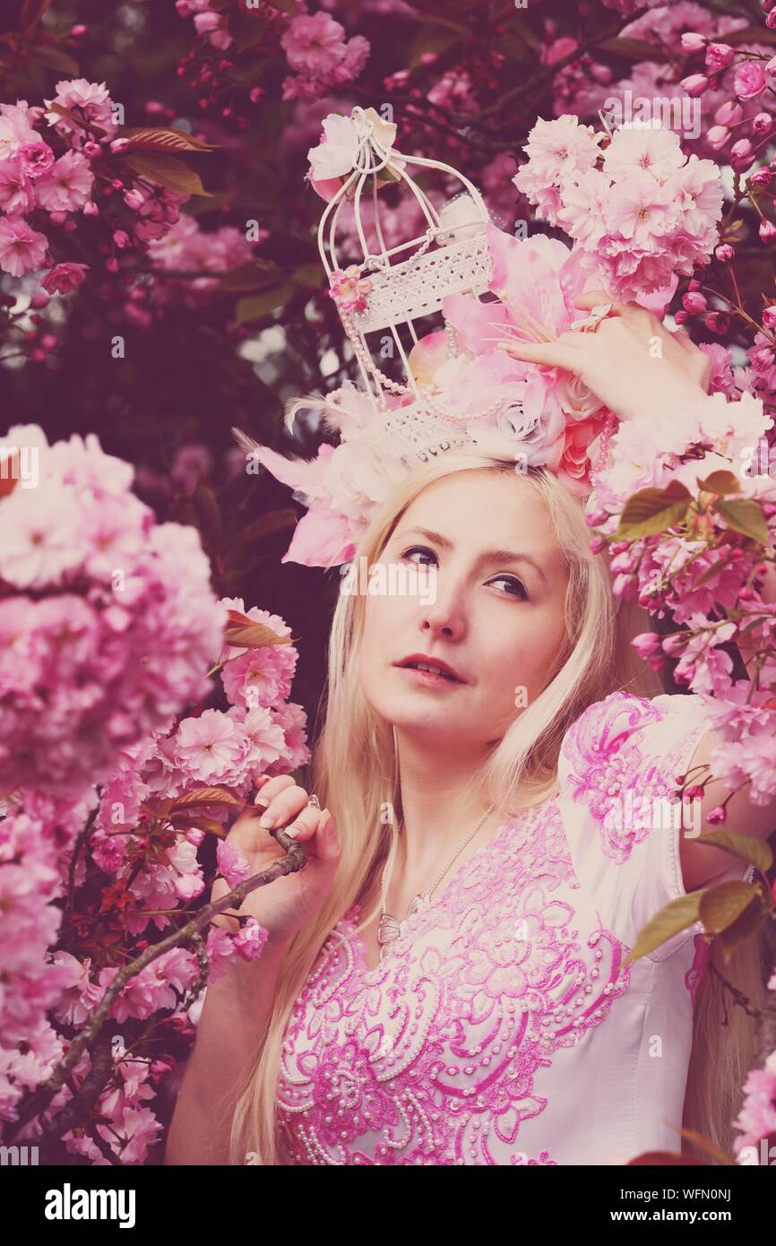 Hermosa mujer de vestido rosado de pie por árbol de cerezo en flor  Fotografía de stock - Alamy