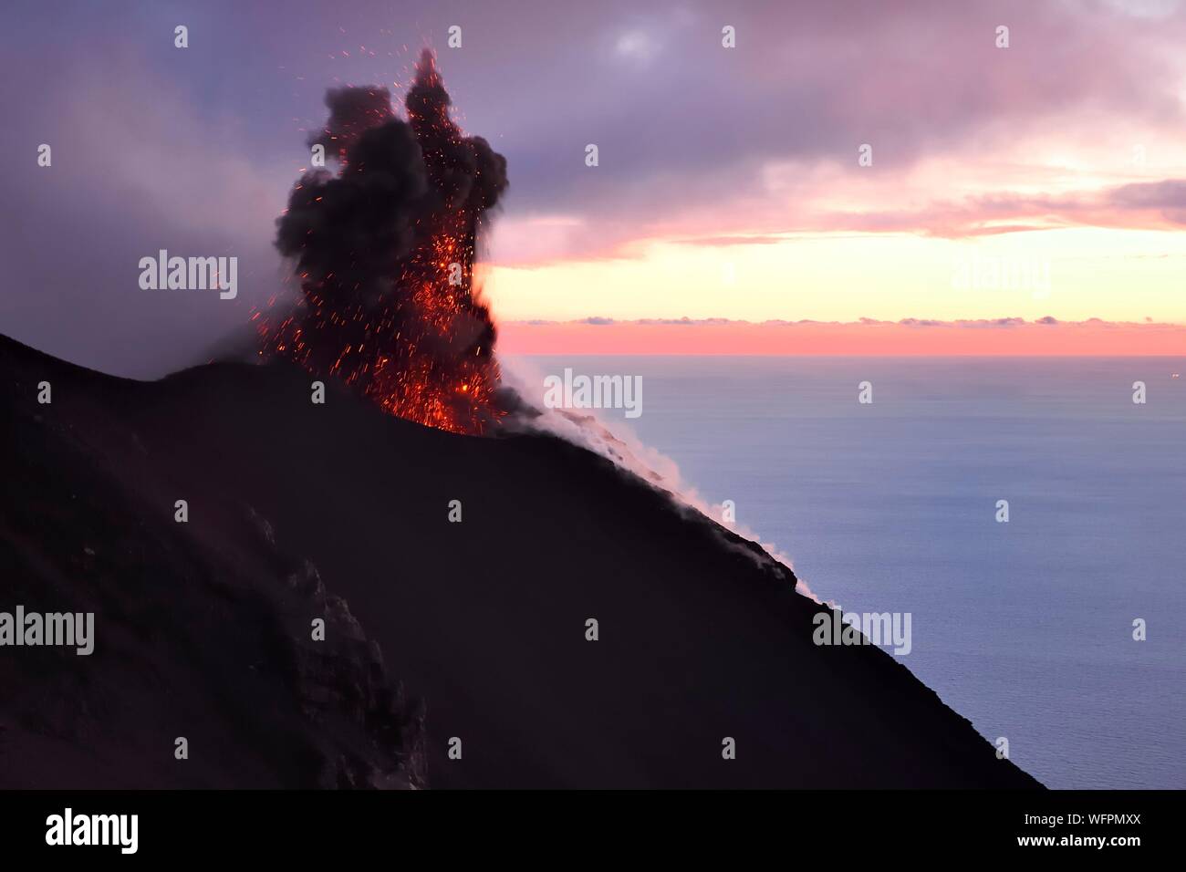 Italia, Sicilia, las Islas Eolias, catalogada como Patrimonio de la Humanidad por la UNESCO, la isla de Stromboli, erupción y proyección de bombas de lava en las laderas del volcán activo al atardecer Foto de stock