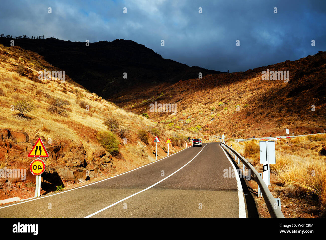 Perspectiva decreciente de carretera pasando a través de las montañas contra el cielo nublado Foto de stock