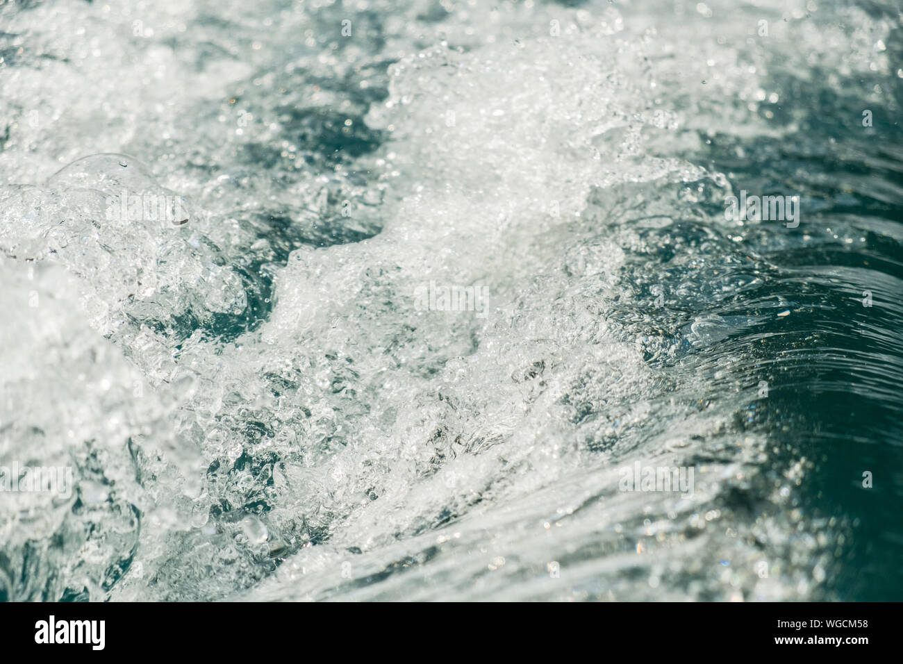 Salpicadura de agua fresca con gotas capturadas en el aire con la superficie del río color turquesa en el fondo Foto de stock