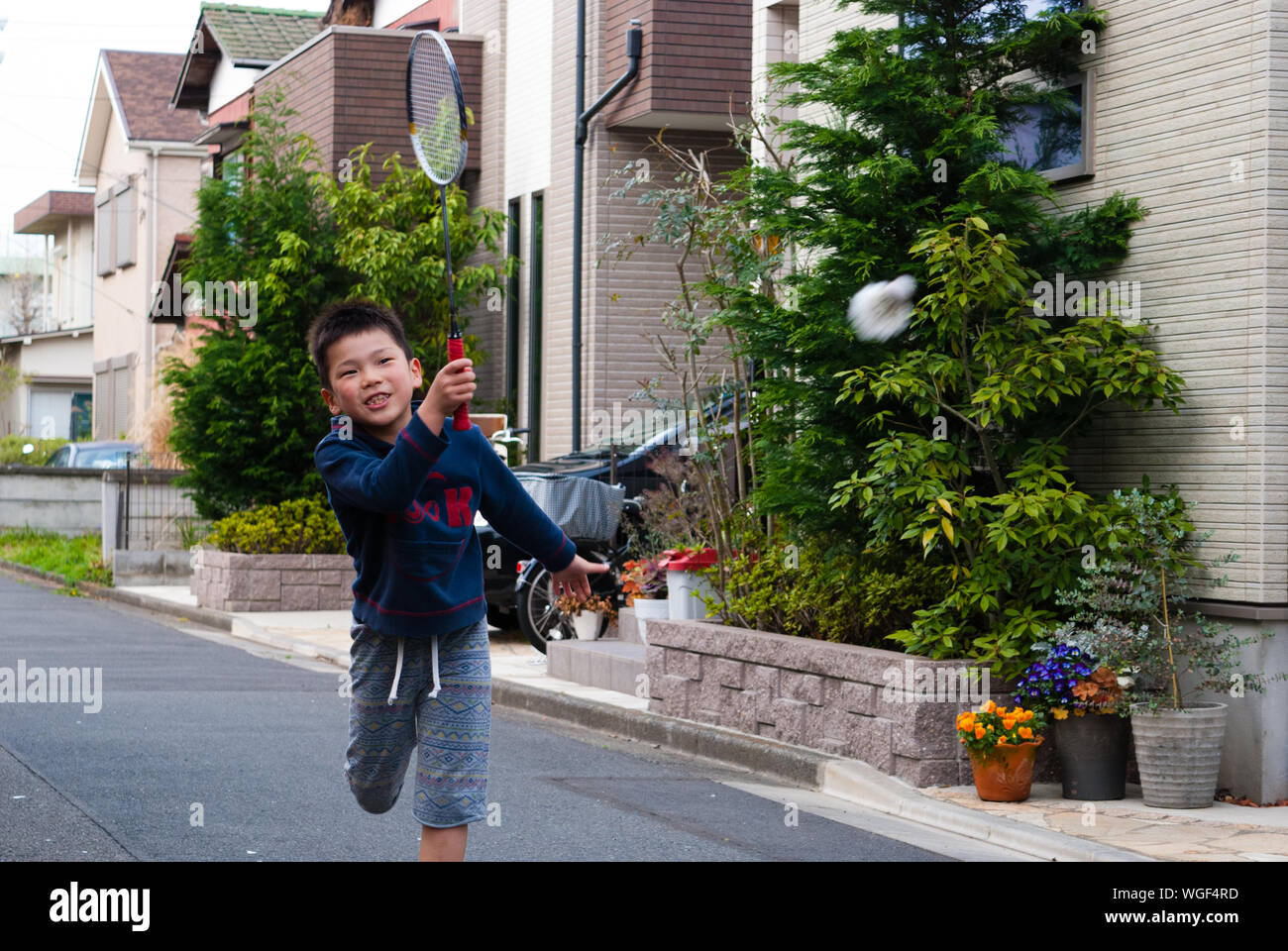 Boy jugar bádminton en la calle por casa Foto de stock