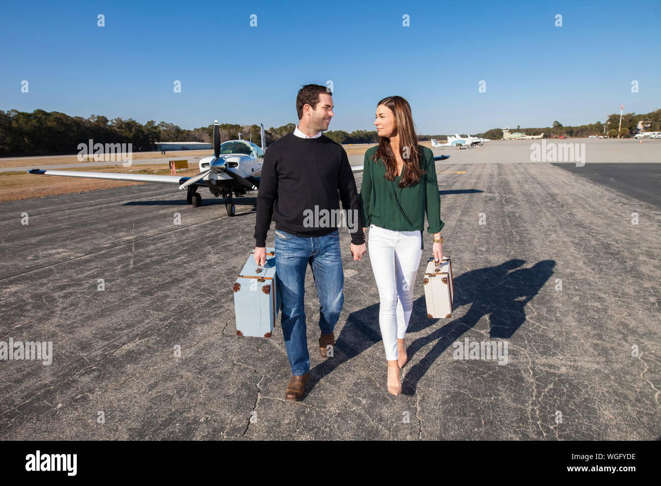 Moda joven pareja a pie de avión privado con equipaje Foto de stock