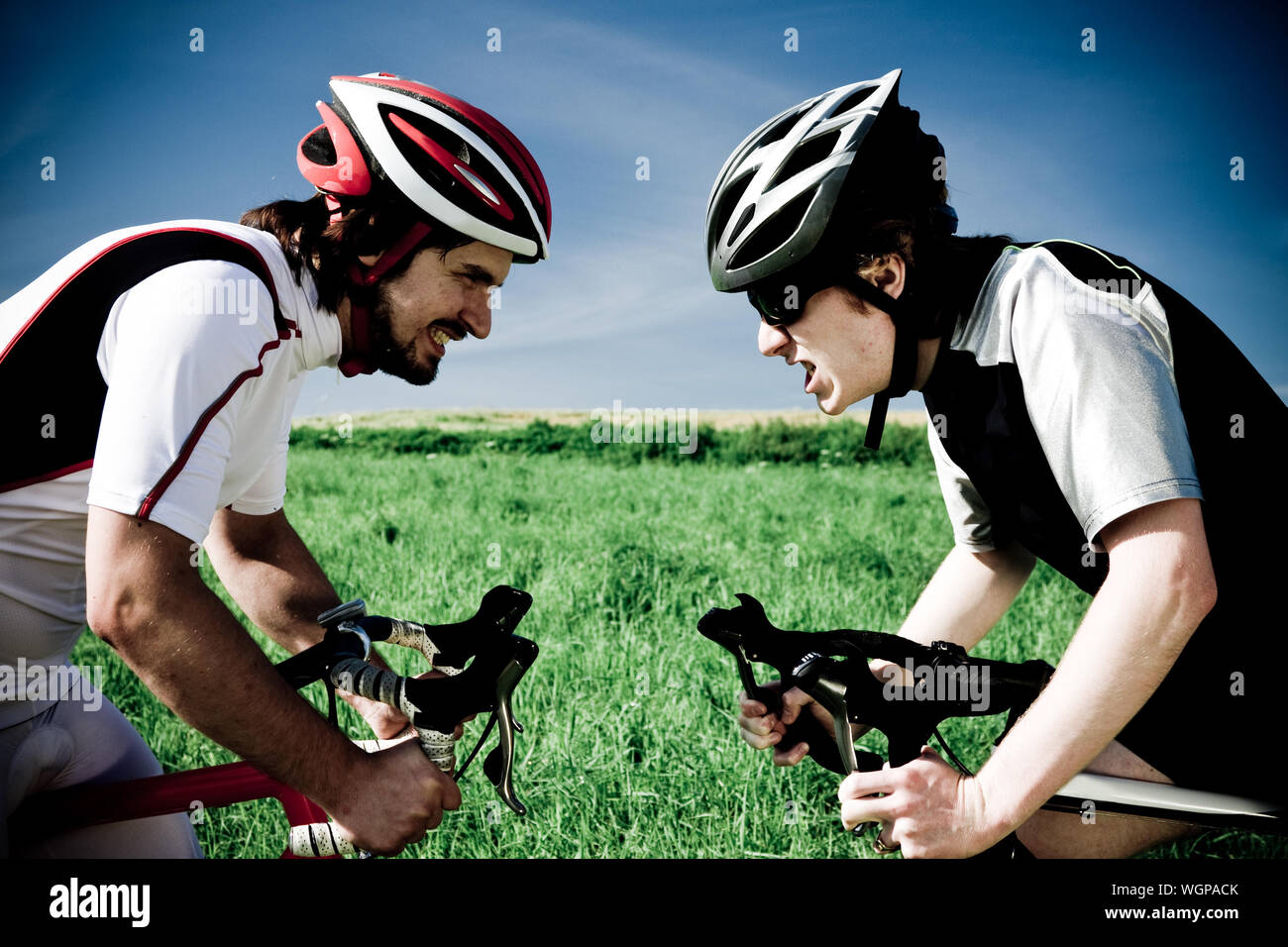 Mediados de los hombres adultos con bicicletas en el campo de hierba contra el cielo Foto de stock