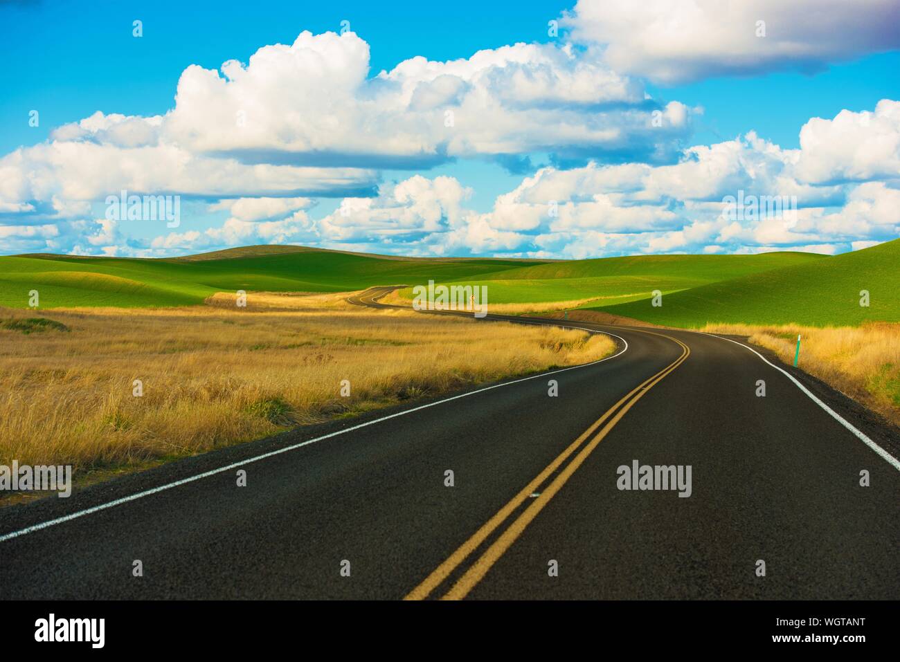 Carretera pasando por paisajes agrícolas contra Sky Foto de stock