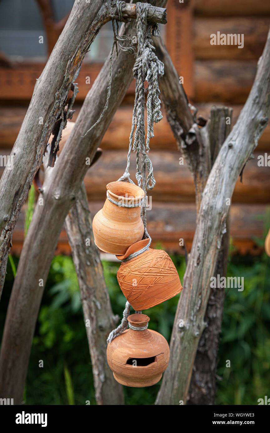 Close-up de un jarrón de cerámica decorado con un bonito dibujo de madera  colgando de una cuerda por encima de una valla de madera. Las ollas de  arcilla Fotografía de stock -