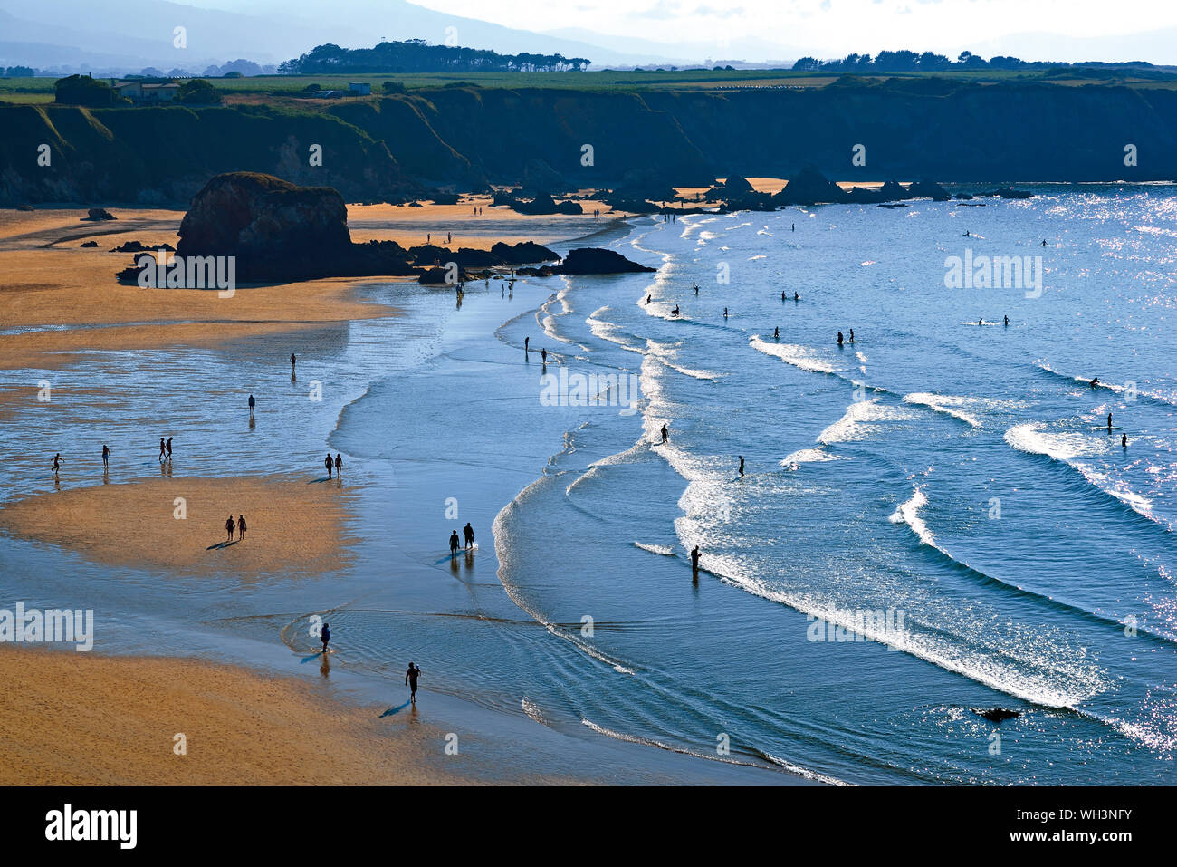 Vistas a la hermosa bahía de playa con arena y rocas visitadas por turistas de baño de verano Foto de stock