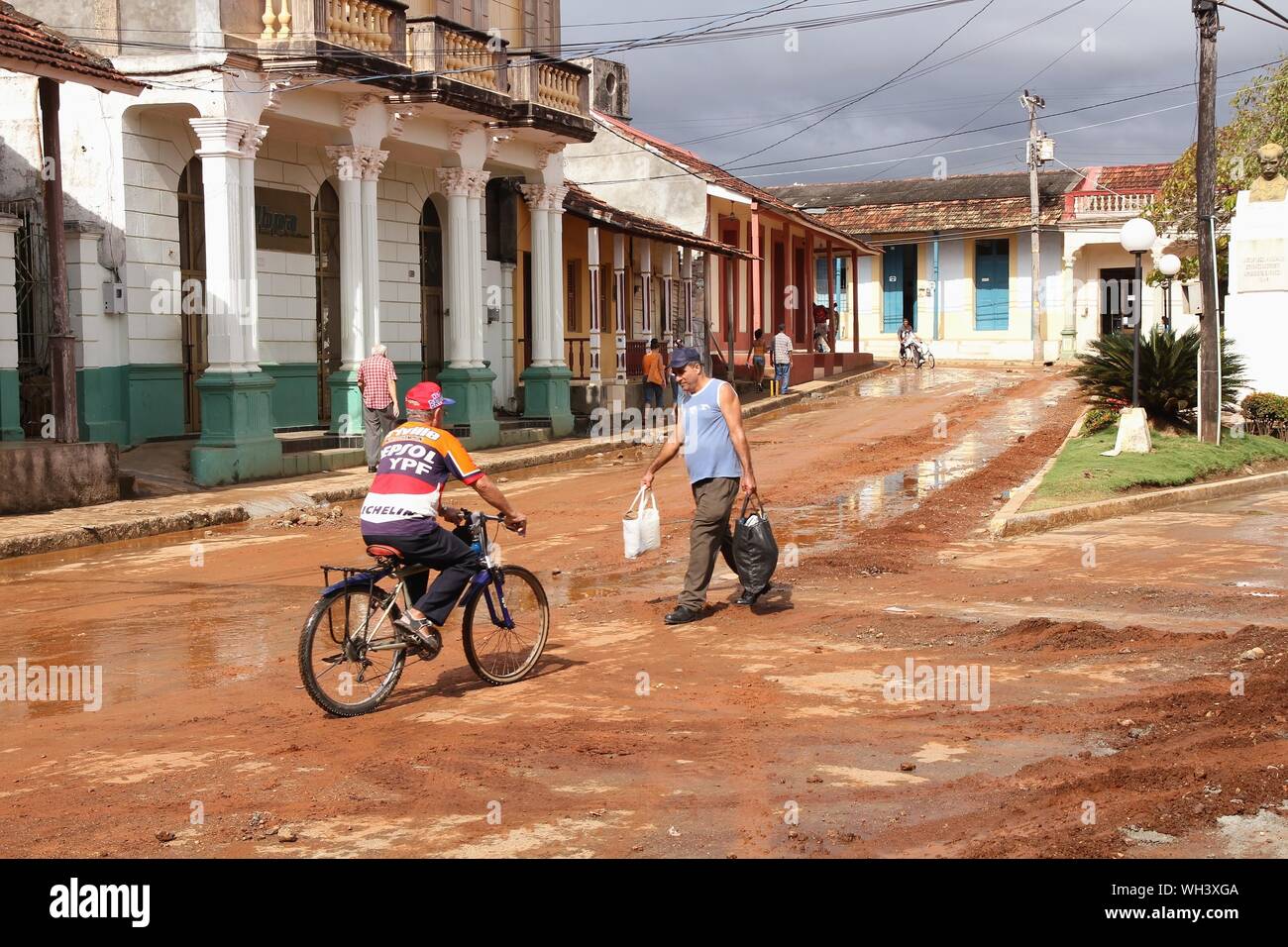 BARACOA, CUBA - Febrero 13, 2011: la gente camina las calles lodosas en Baracoa, Cuba. Baracoa, cuenta con una población de 81,794. Foto de stock