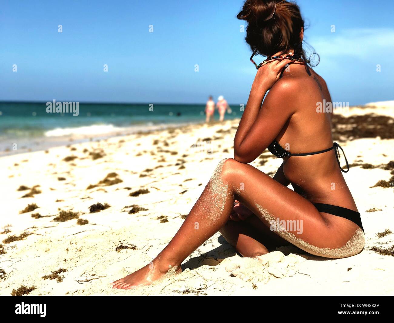 Vista lateral de la mujer vistiendo Bikini relajándose en la playa en día soleado Foto de stock