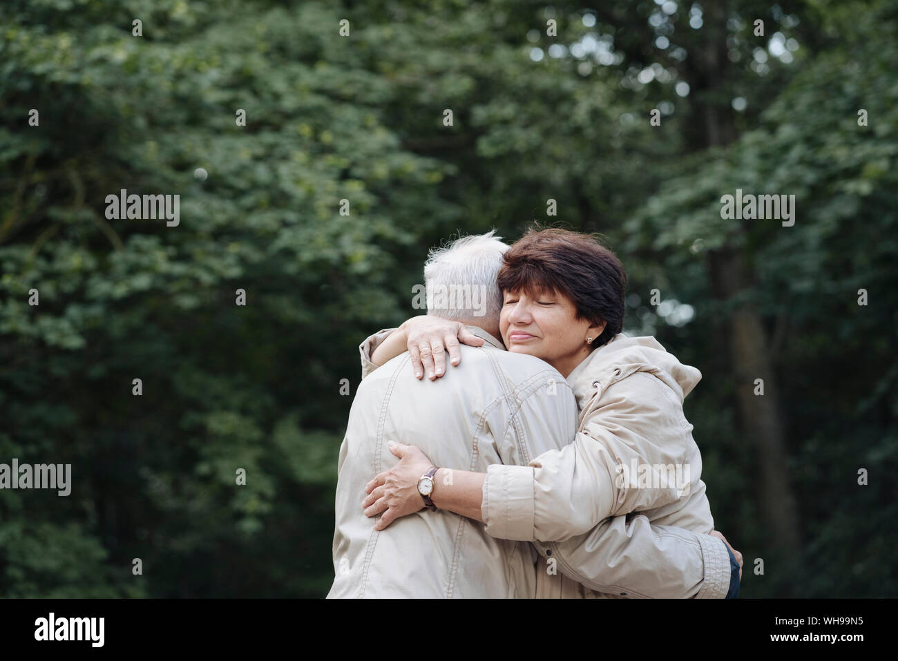 Retrato de mujer mayor abrazando a su marido en el bosque Foto de stock