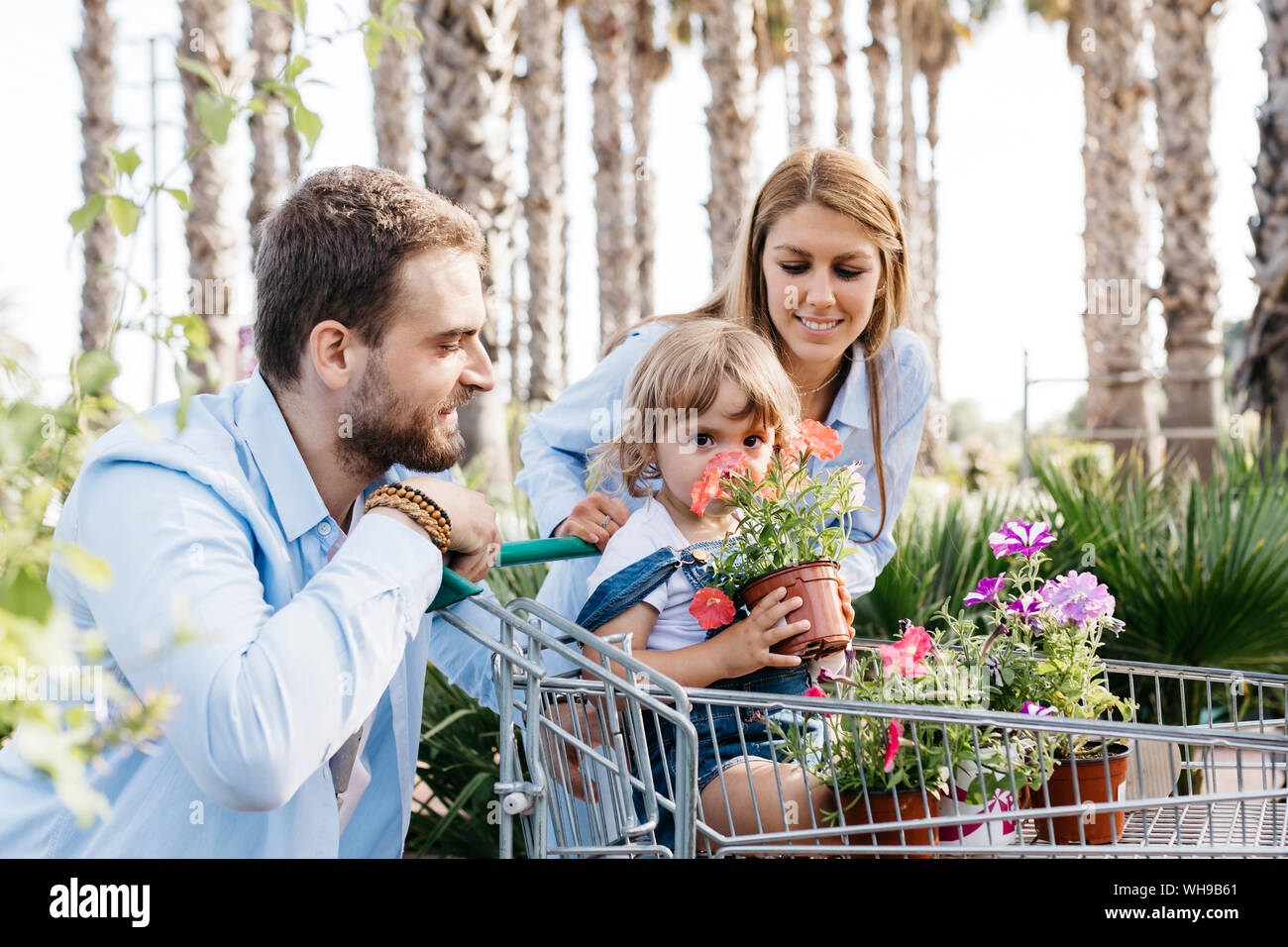 Familia comprar plantas en un centro de jardinería con la hija en compras oliendo una flor Foto de stock