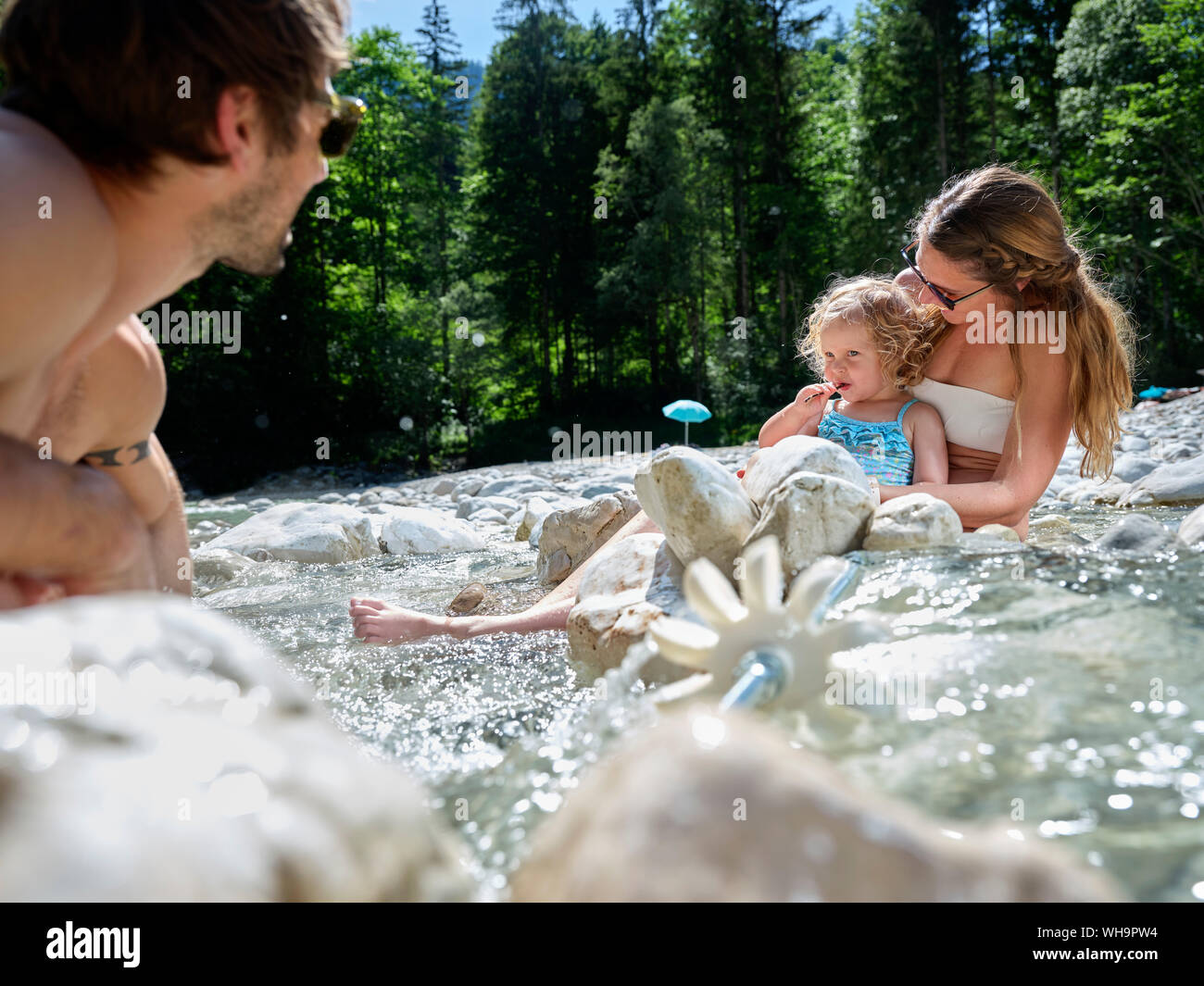 Familia con la hija de fijación rueda de agua en un arroyo de montaña Foto de stock