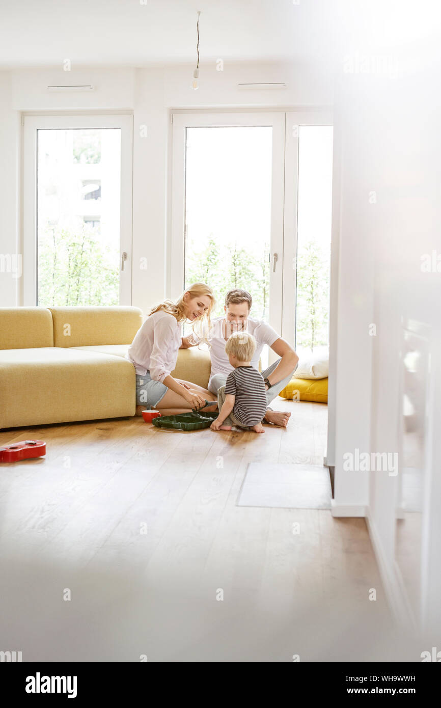 Familia feliz con un hijo jugando en la sala de estar de su nuevo hogar. Foto de stock