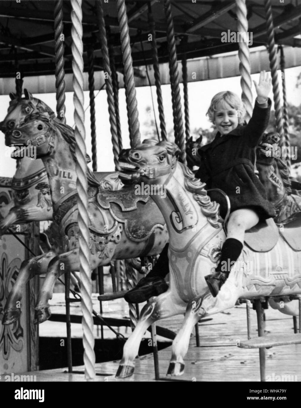 Una niña alegre en un merry go round en una feria de atracciones Foto de stock