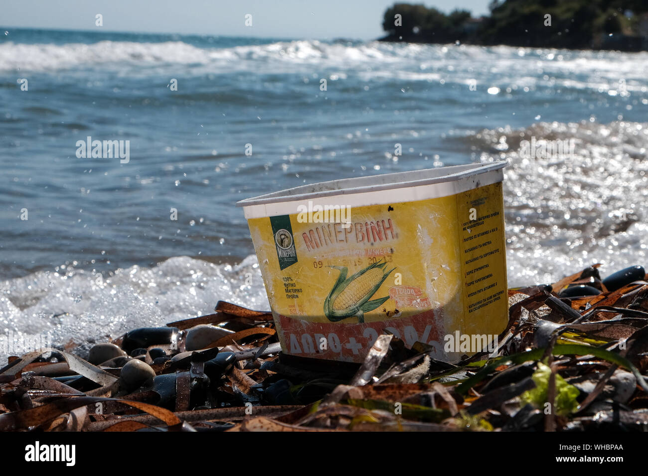 Un contenedor de dulce de plástico desechados en la playa con agua la decoloración y daño ahora añadiendo a la contaminación del océano y daños ambientales. Foto de stock