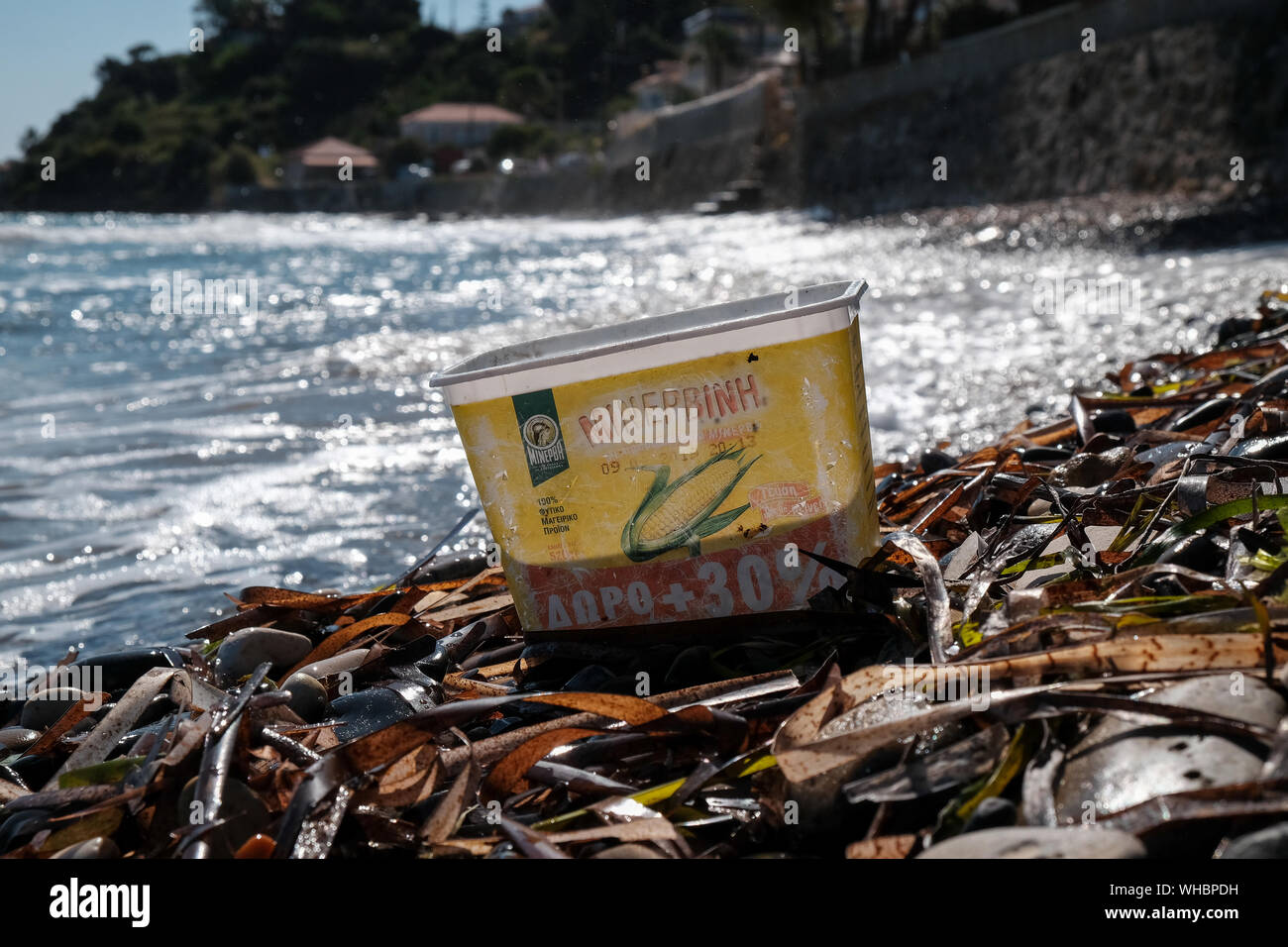 Un contenedor de dulce de plástico desechados en la playa con agua la decoloración y daño ahora añadiendo a la contaminación del océano y daños ambientales. Foto de stock