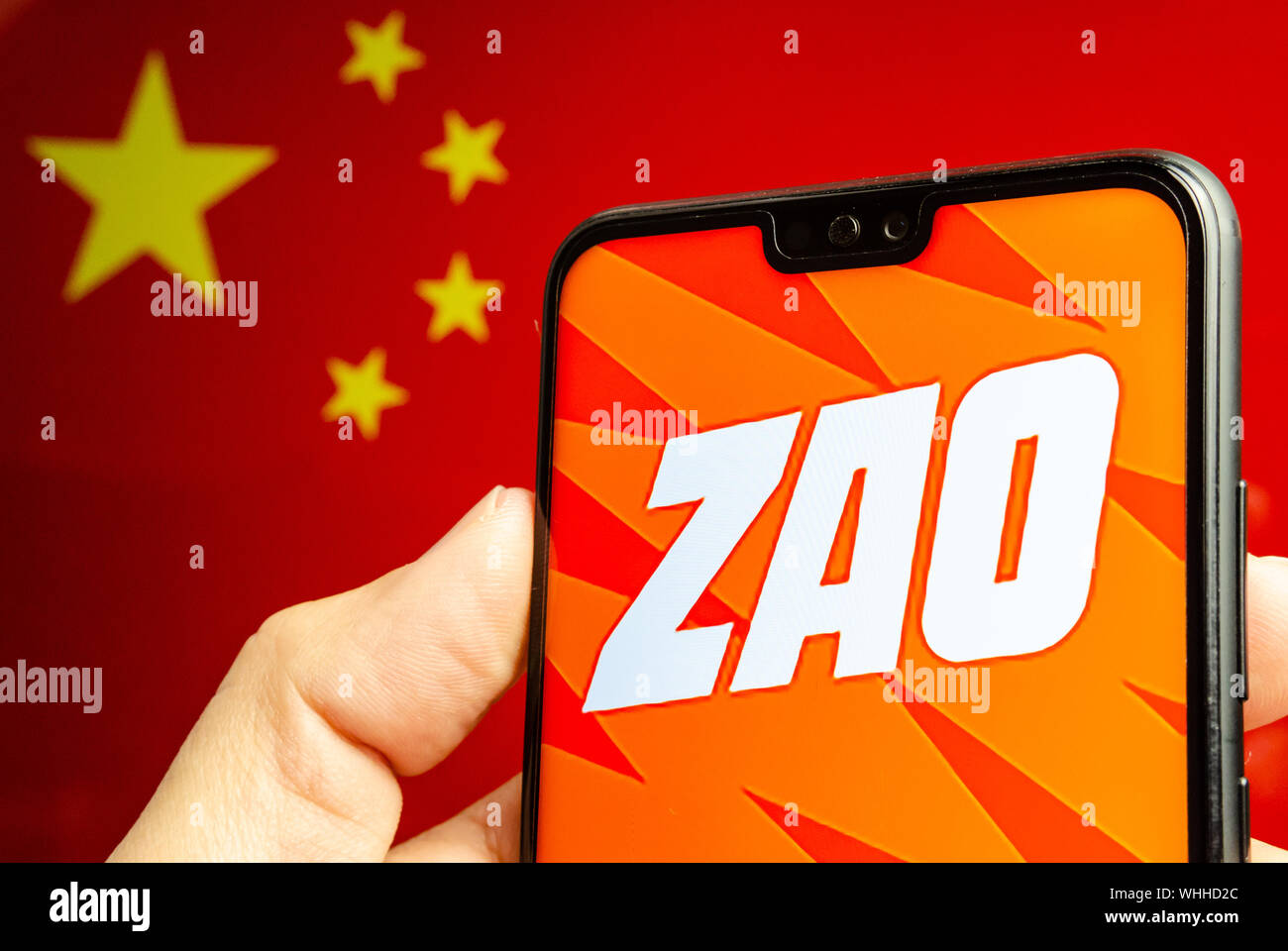 Mano sostiene un smartphone con ZAO app logo. El pabellón de China borrosa  en el fondo. Zao es actualmente un número una entretenida app en China  Fotografía de stock - Alamy