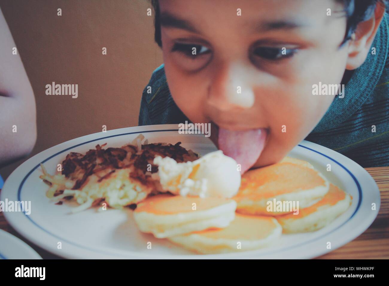 Close-up de chico lindo lamiendo los alimentos en la placa Foto de stock