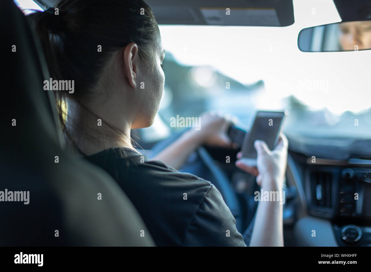 Una persona que utiliza el teléfono mientras se conduce un automóvil. Los mensajes de texto y la conducción. Foto de stock