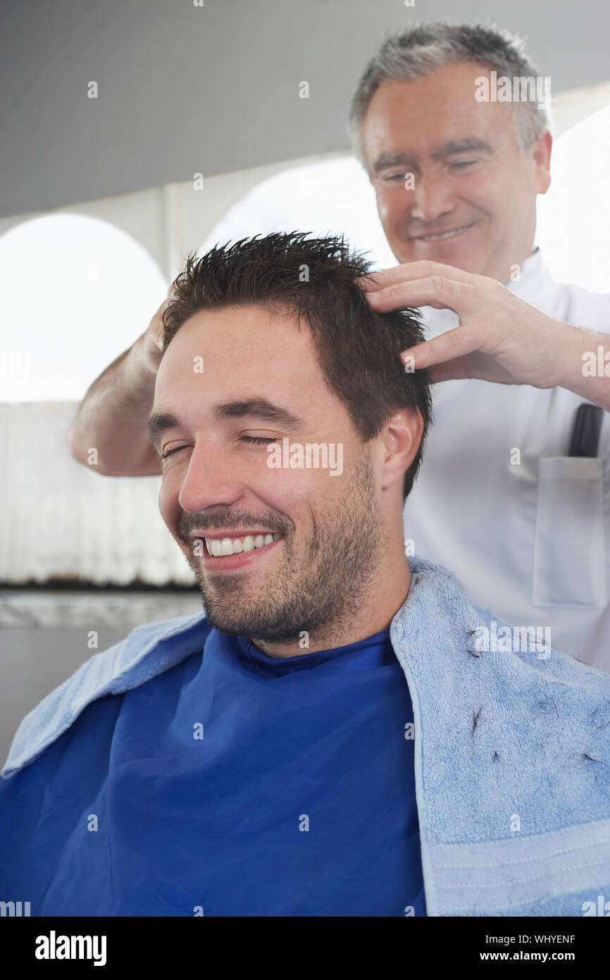 Hombre feliz recibiendo un masaje de cabeza de peluquería después del corte  de pelo Fotografía de stock - Alamy