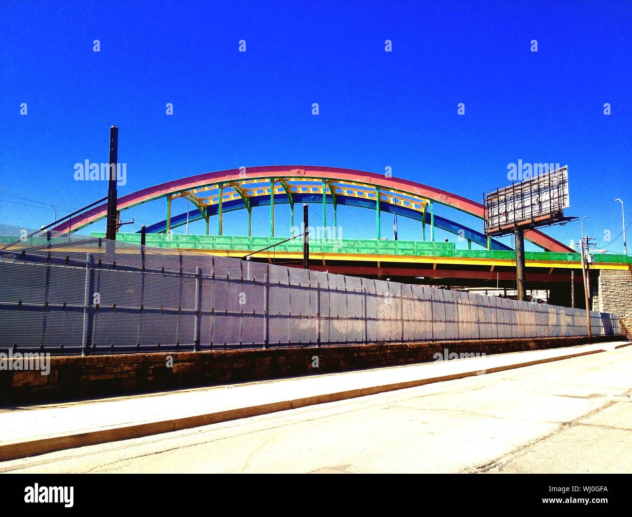 Puente en arco pintado en colores del arco iris en el cielo claro Foto de stock