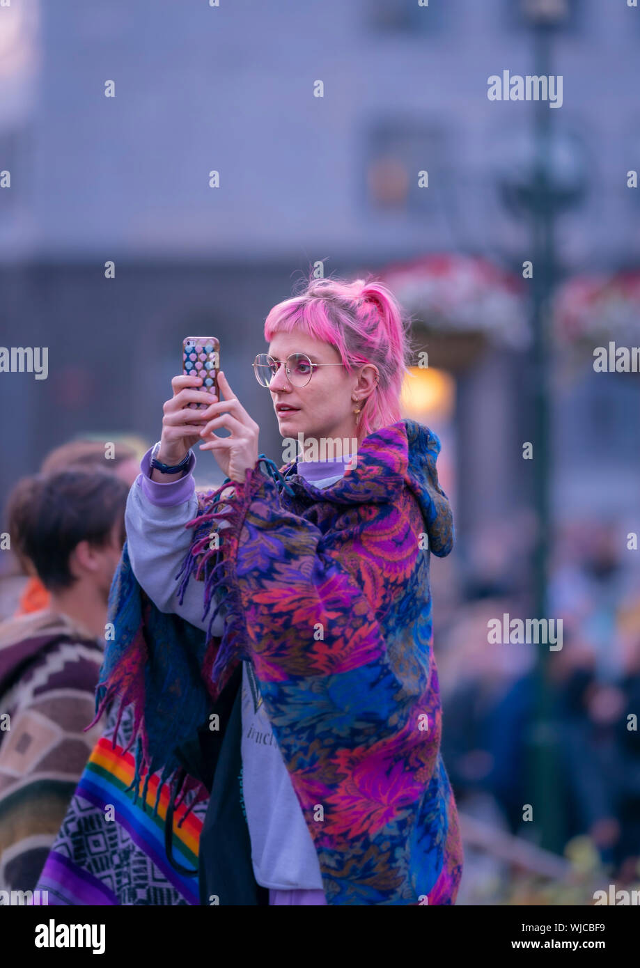 Chica tomando una fotografía con un teléfono inteligente, o Menningarnott Día Cultural, Reykjavik, Iceland. Chica busca en su teléfono inteligente, o Menningarnott Cultur Foto de stock
