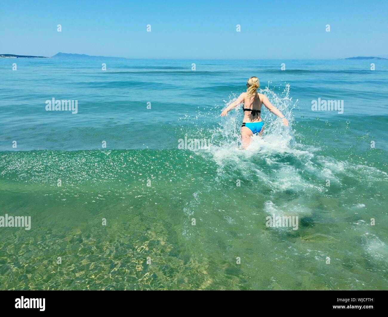 Vista trasera de la mujer en Bikini caminando por la playa Foto de stock