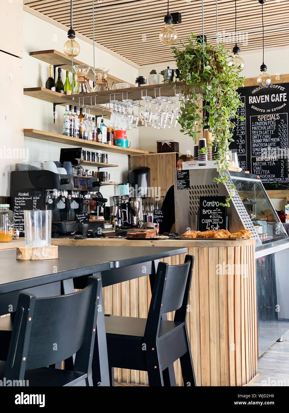 una mesa de madera negra con sillas, máquinas de café, vasos y botellas en  una cafetería Fotografía de stock - Alamy