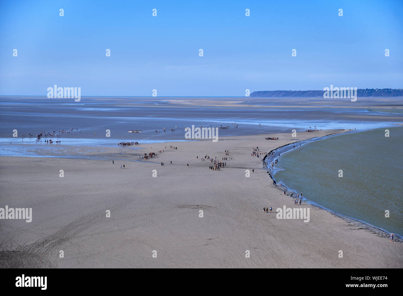 Peregrinos caminando a través de Mont St Michel durante la marea baja. Foto de stock