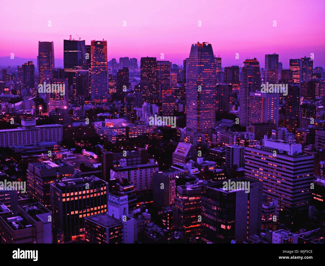 Las iluminaciones de los edificios contra el cielo púrpura en la ciudad al atardecer Foto de stock