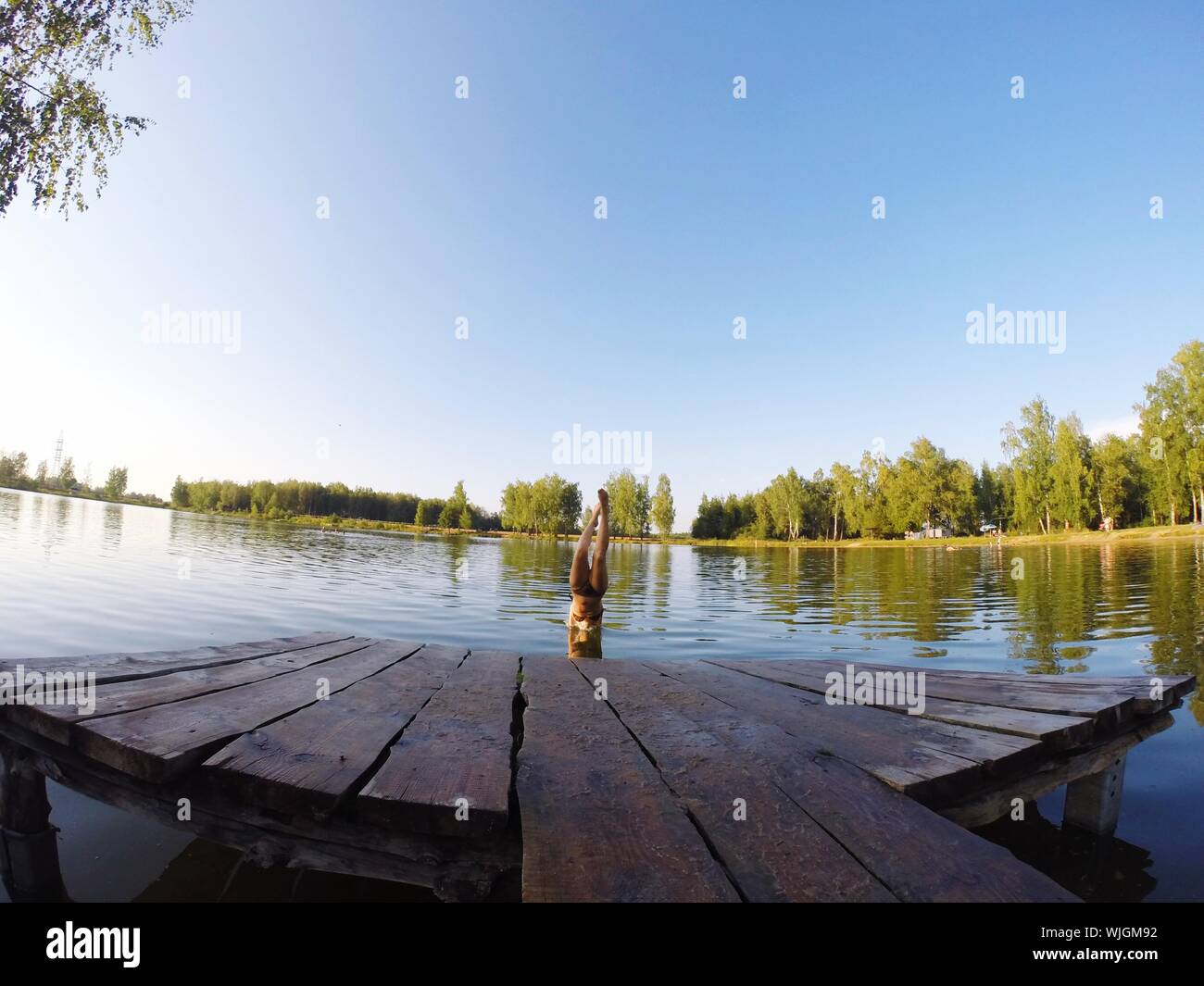 Mujer joven buceo en el lago contra el cielo claro Foto de stock