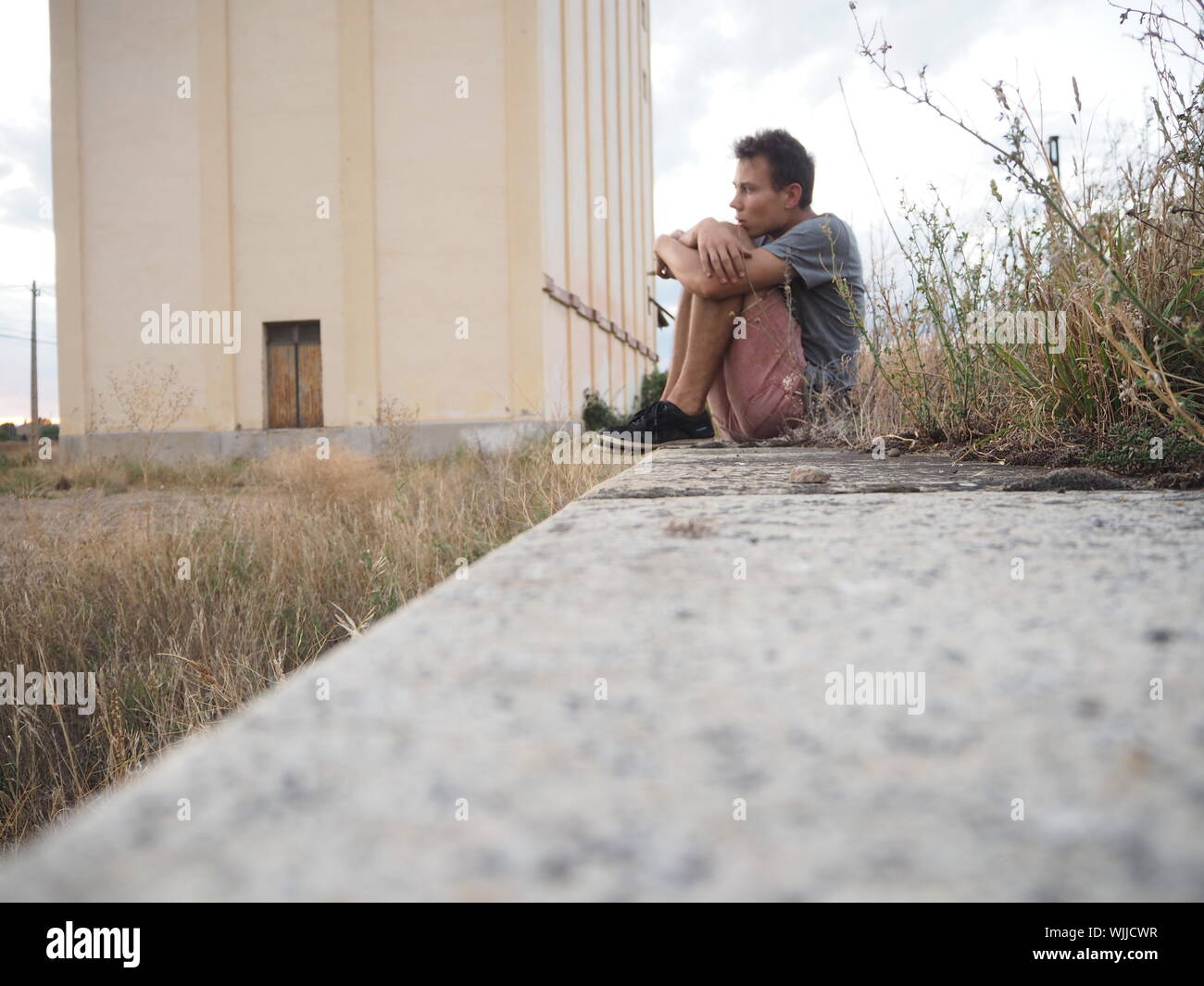 La superficie vista del hombre sentado sobre el muro de retención Foto de stock