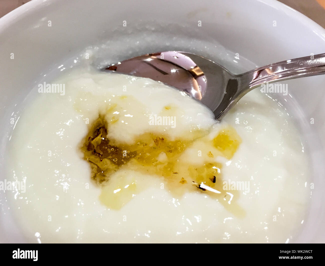Un alto ángulo de visualización de la miel y el yogur con una cuchara en el tazón Foto de stock