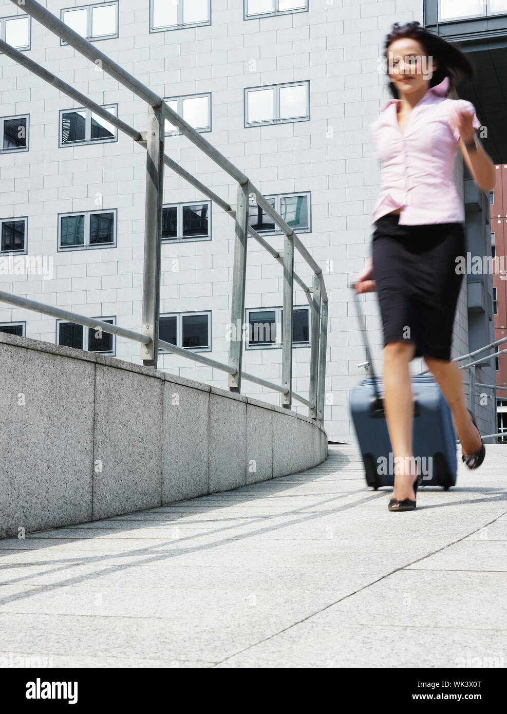 Mujer de negocios corre fuera de la oficina con bolsa trolley Fotografía de  stock - Alamy