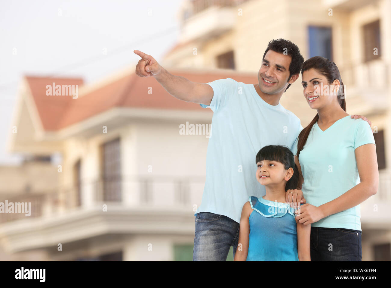 Hombre mostrando algo a su familia frente a su casa Foto de stock