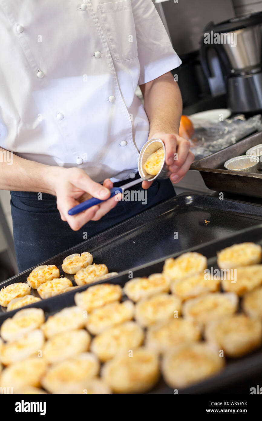 El chef prepara postres quitarlos ramekins individuales o moldes y colocarlos en una bandeja en una cocina comercial Foto de stock