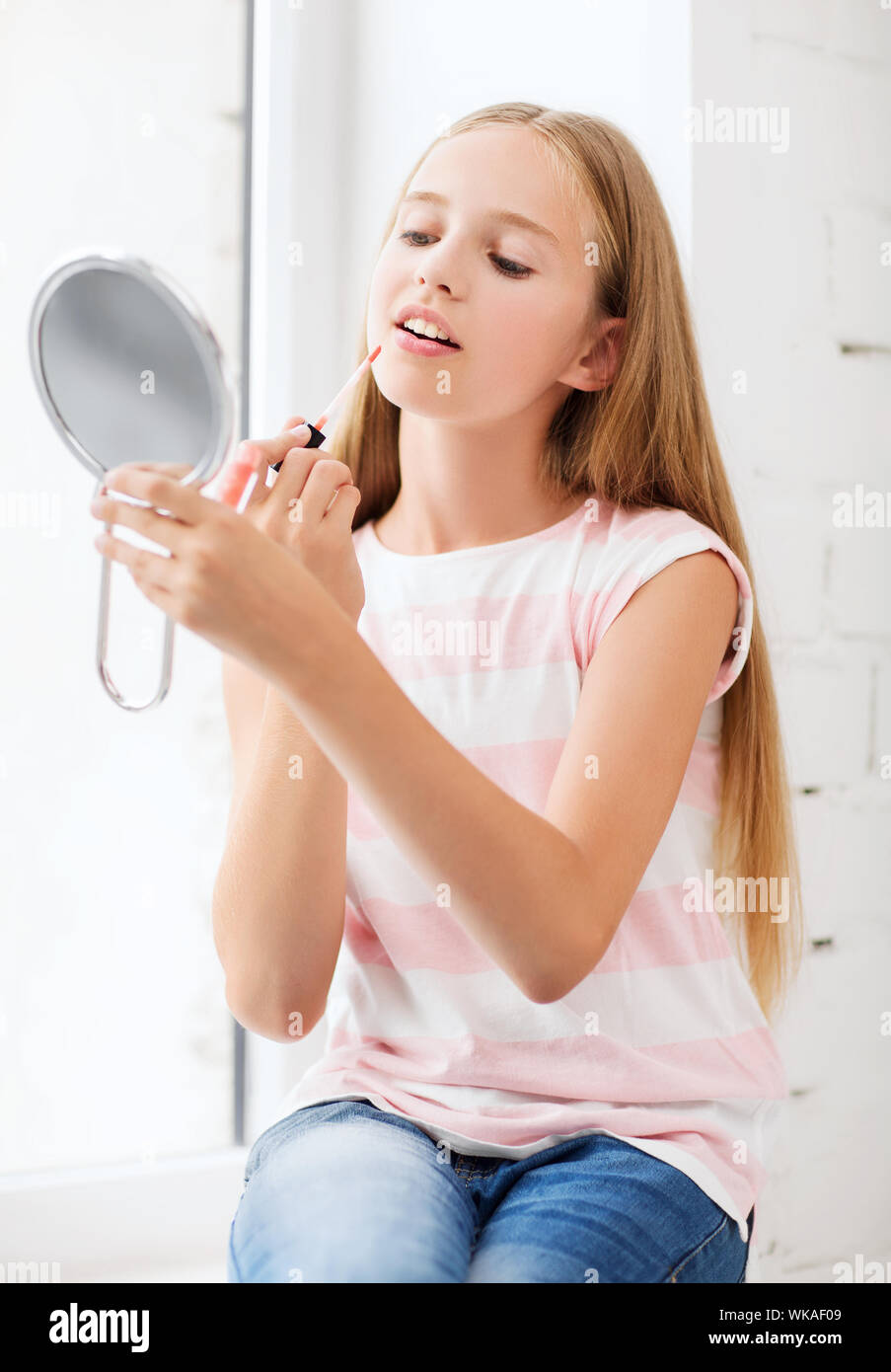 Adolescente con lip gloss y espejo Foto de stock