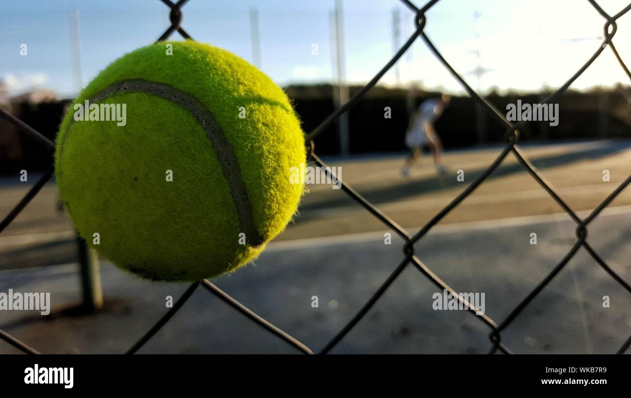 Close-up de bola verde contra Chainlink valla en día soleado Foto de stock