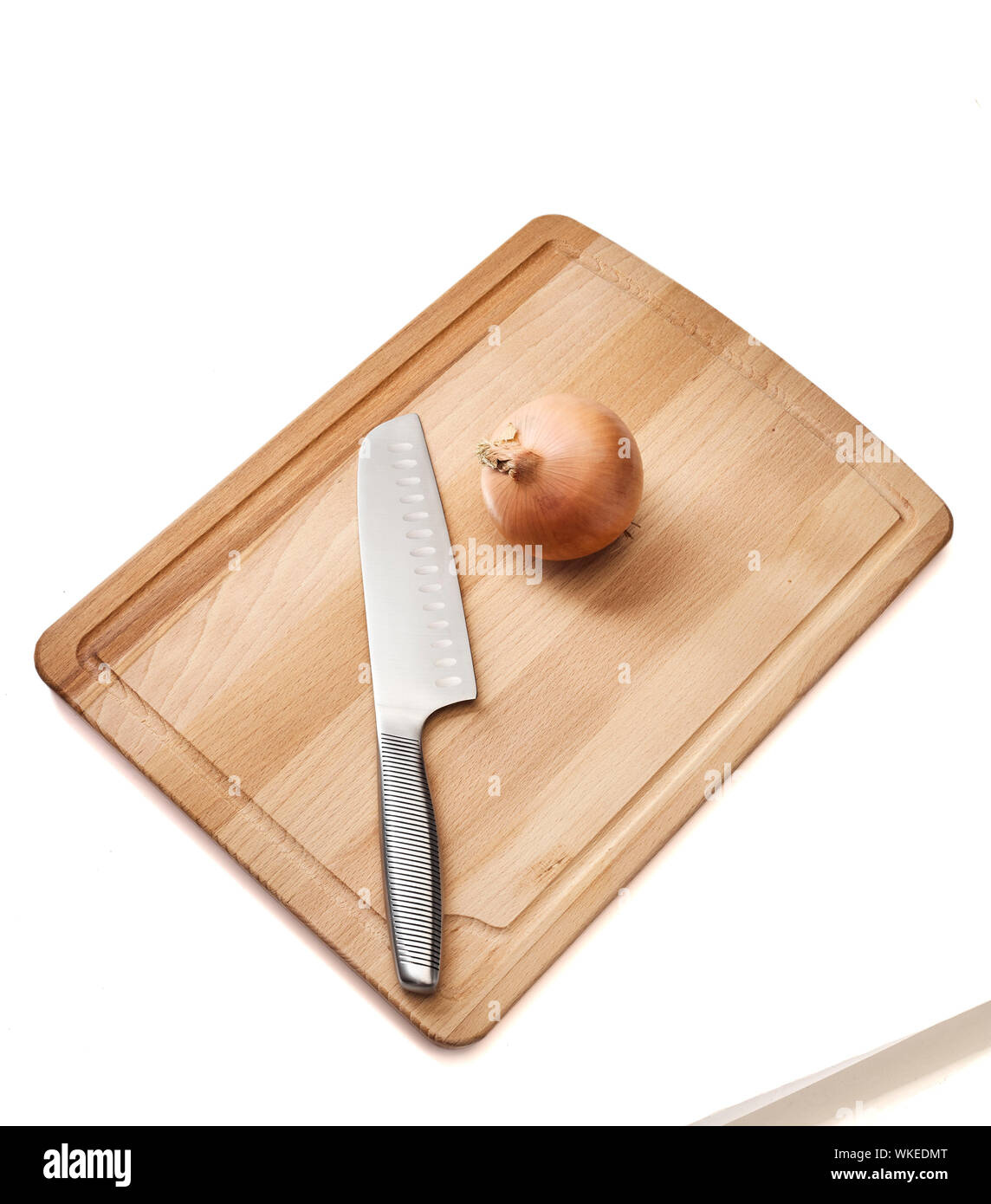 Un alto ángulo de visualización de cebolla con placa de corte y la cuchilla sobre fondo blanco. Foto de stock
