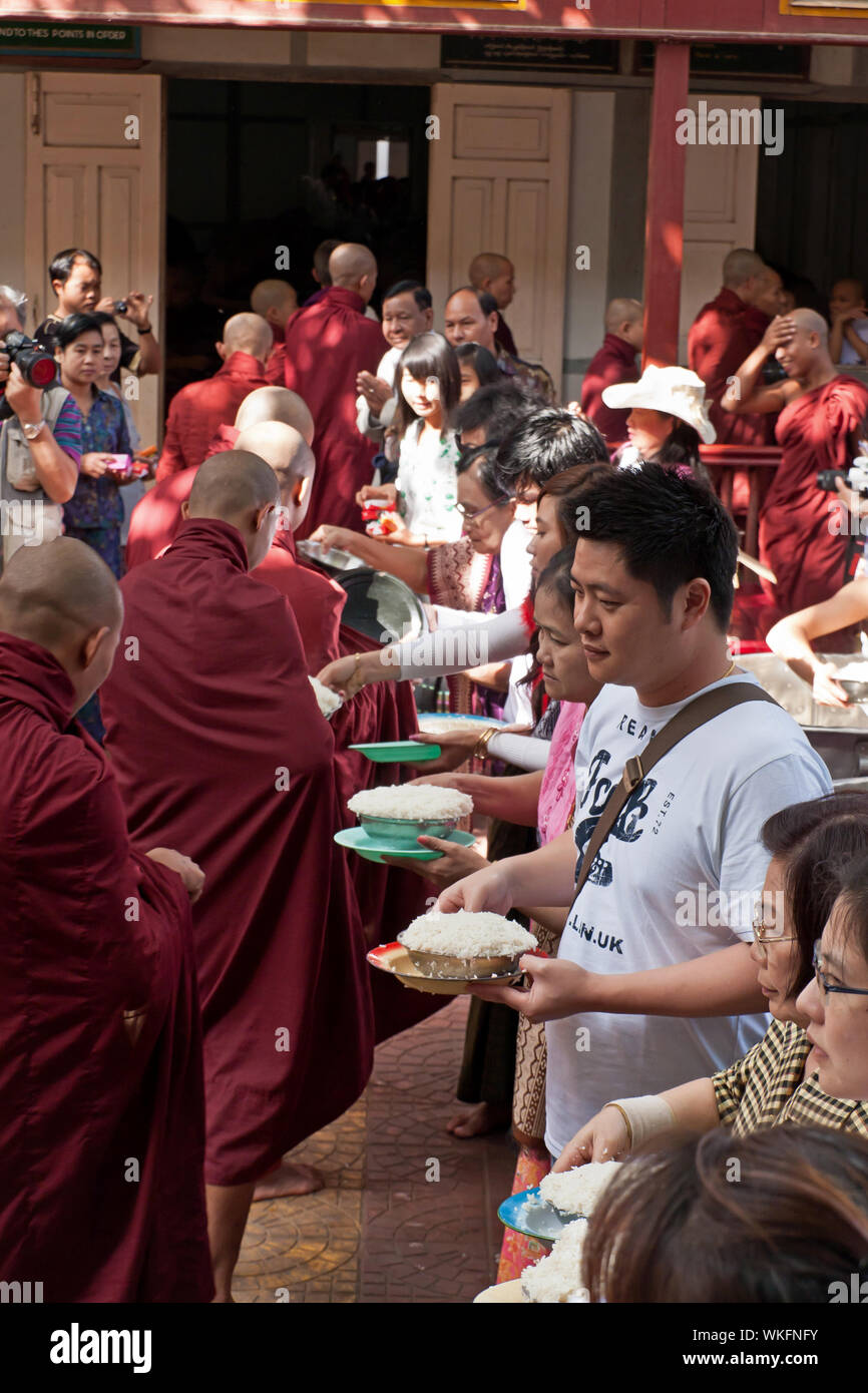 Turistas que distribuyen comida durante el almuerzo de los monjes budistas más grandes del mundo en el monasterio de Mahagandayon, Mandalay Foto de stock