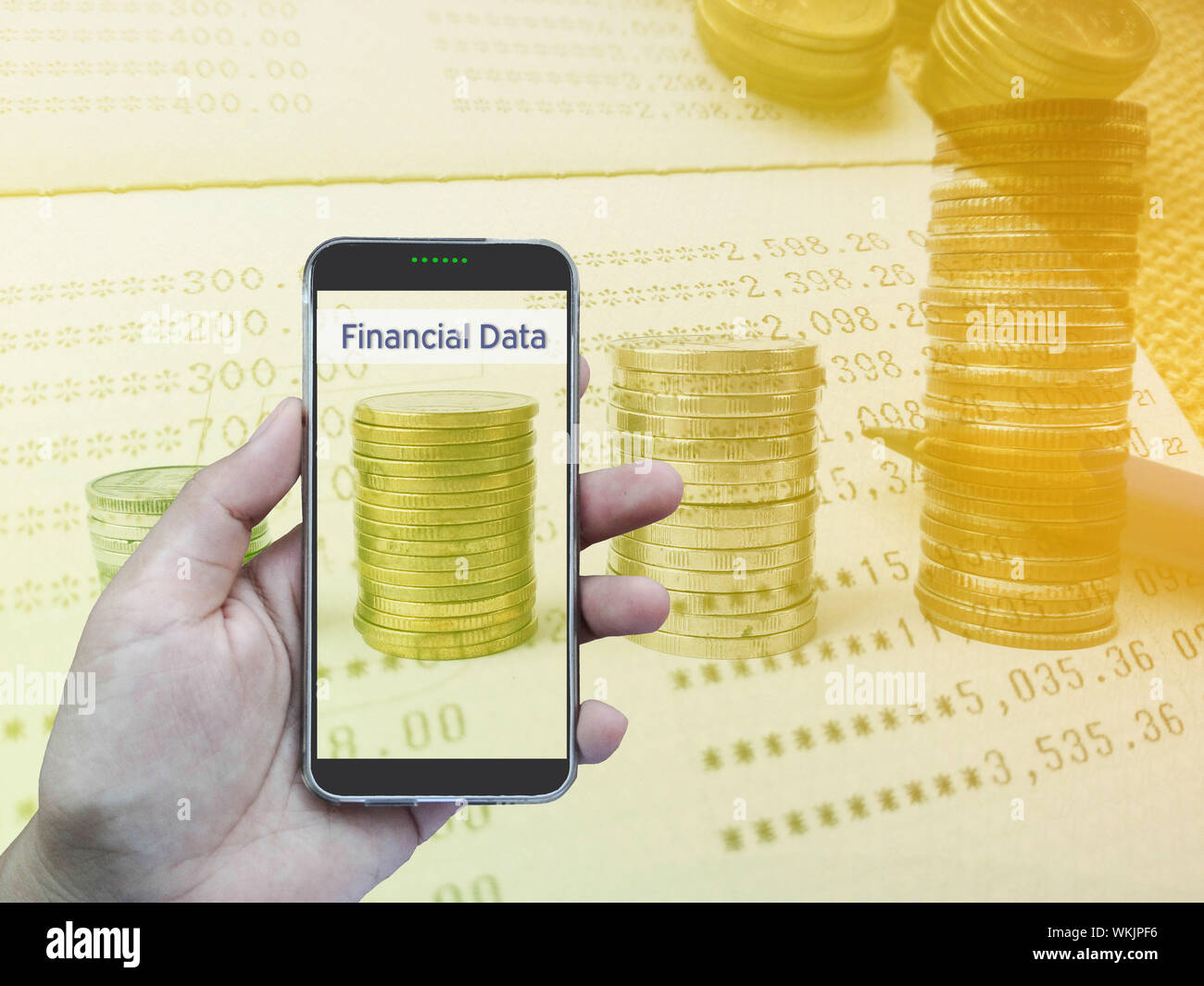 Imagen compuesta digital de mano sujetando el teléfono móvil contra cifras financieras Foto de stock
