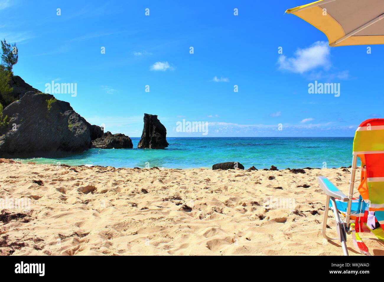 Captura conceptual de un idílico destino vacacional. Una apartada playa Paraíso en las Bermudas, con sol, mar color turquesa, arena blanca, sombrilla y tumbona. Foto de stock
