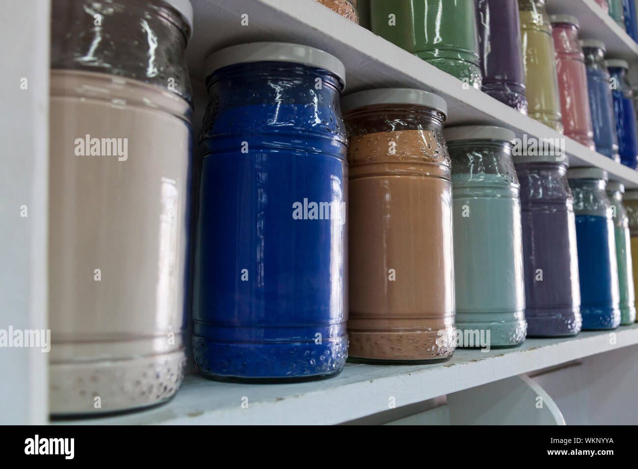 Estanterías con frascos de vidrio de pigmentos coloridos Foto de stock