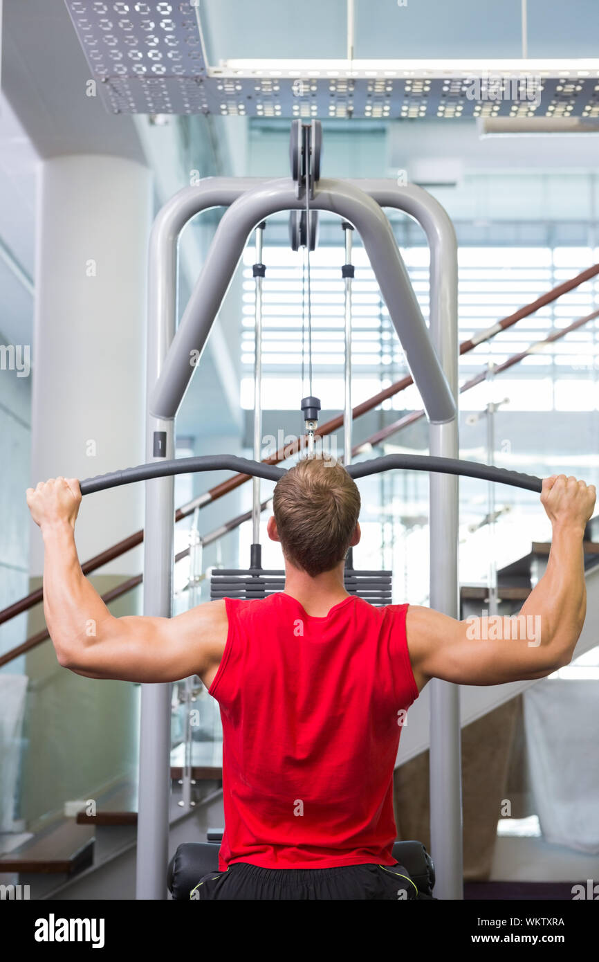 Hombre Fuerte usando las máquinas de musculación de brazos en el gimnasio  Fotografía de stock - Alamy