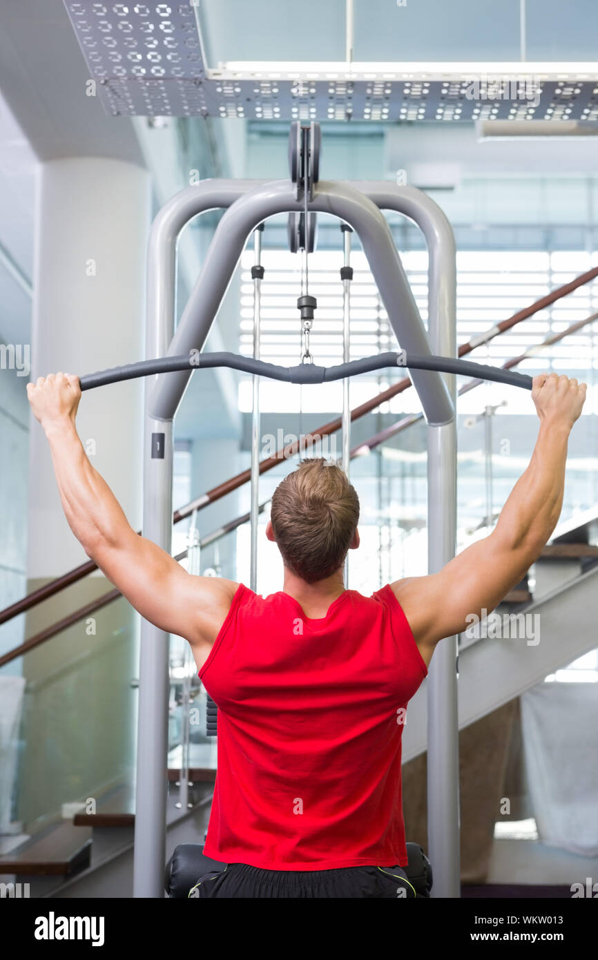 Hombre Fuerte usando las máquinas de musculación de brazos en el gimnasio  Fotografía de stock - Alamy