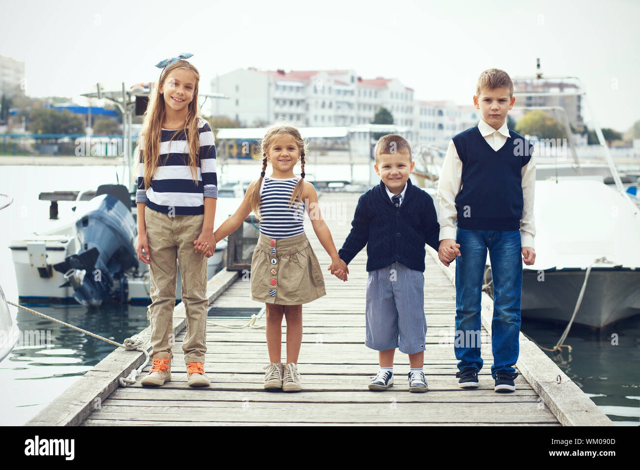 Grupo de 4 Moda niños vistiendo ropa marina en estilo náutico, posando en  el puerto marítimo y tomados de la mano Fotografía de stock - Alamy