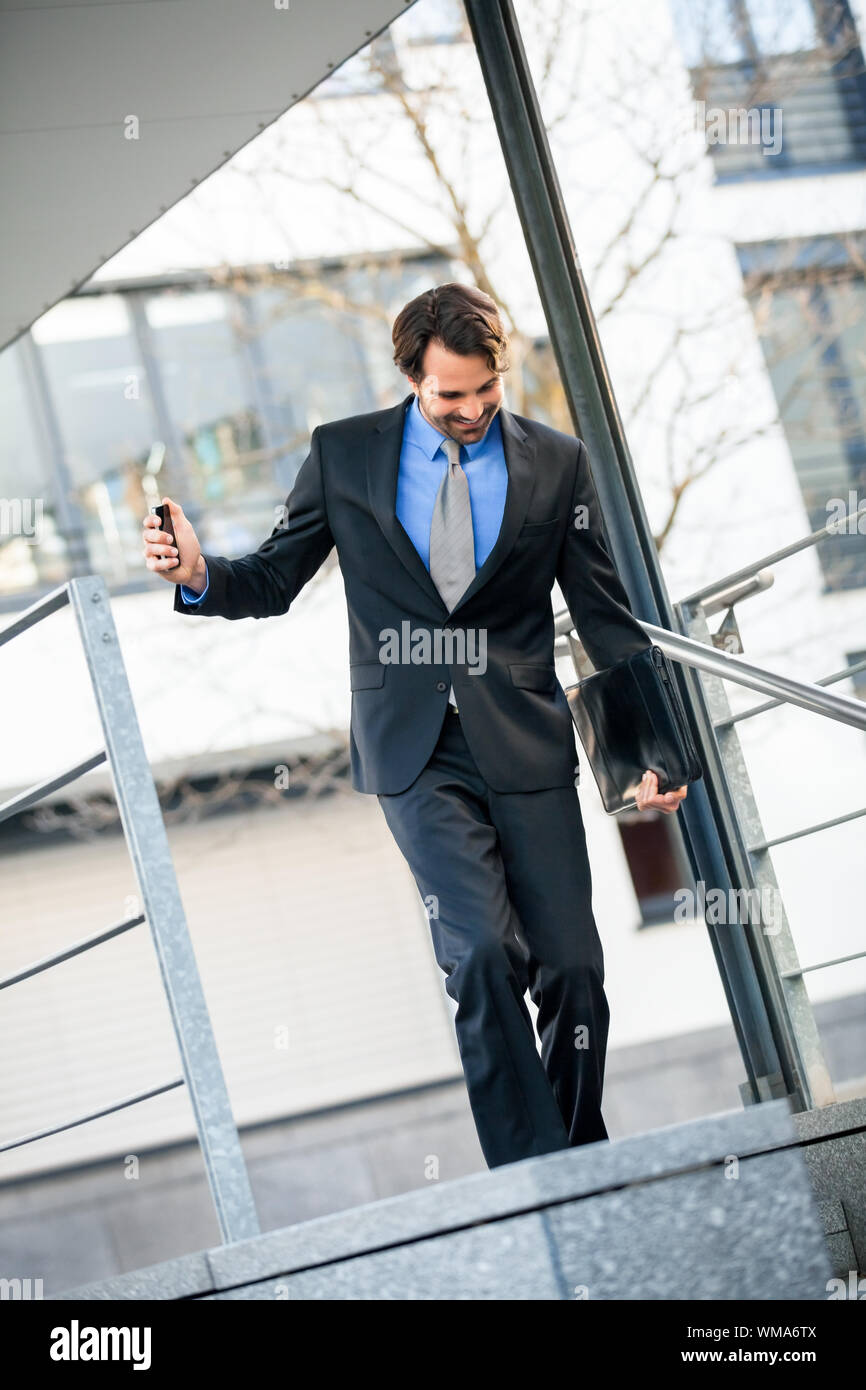 Empresario sonriente caminando escaleras abajo Foto de stock