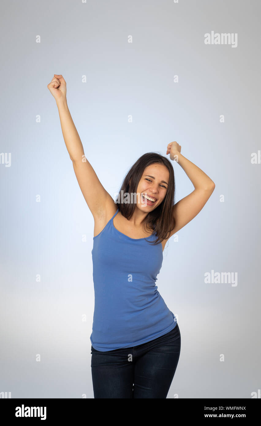 Retrato de joven mujer atractiva celebrando el éxito de la ganadora o se siente afortunado y gozosa celebración bailando y haciendo gestos con los brazos aislados Foto de stock