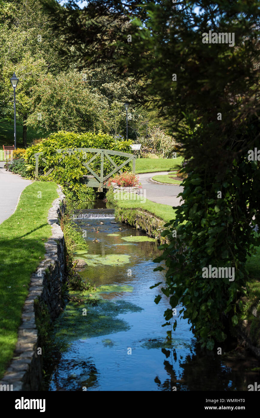 Puente ornamental sobre un pequeño río en una soleada Trenance Gardens en Newquay en Cornualles. Foto de stock